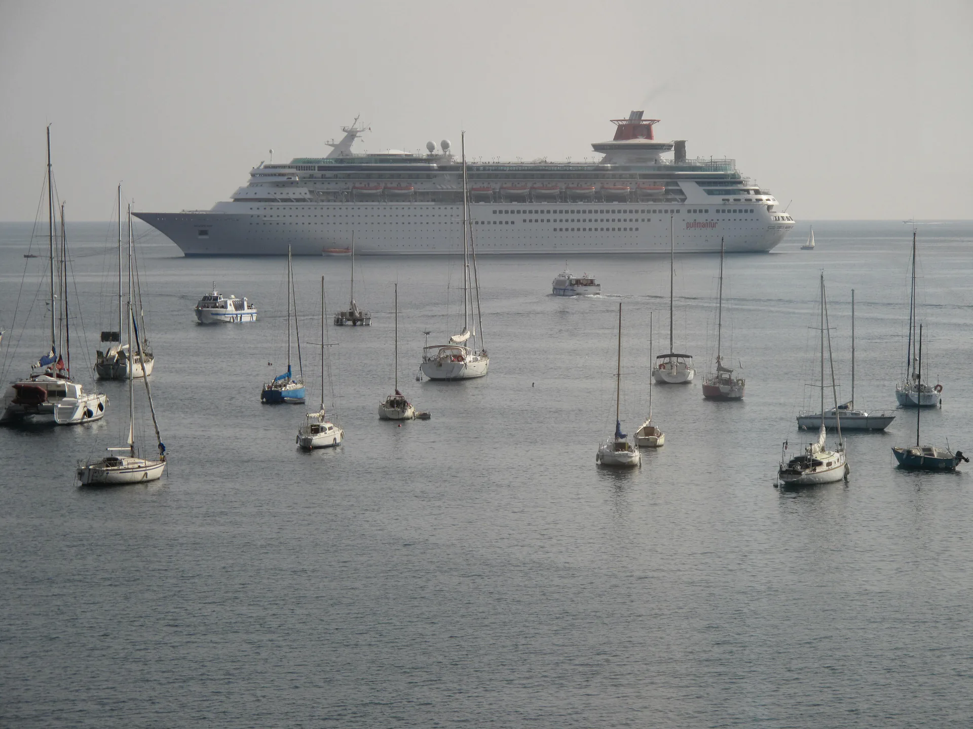 Cruise ship anchored in the bay at Villefranche-sur-Mer with the colourful French Riviera harbour and hills